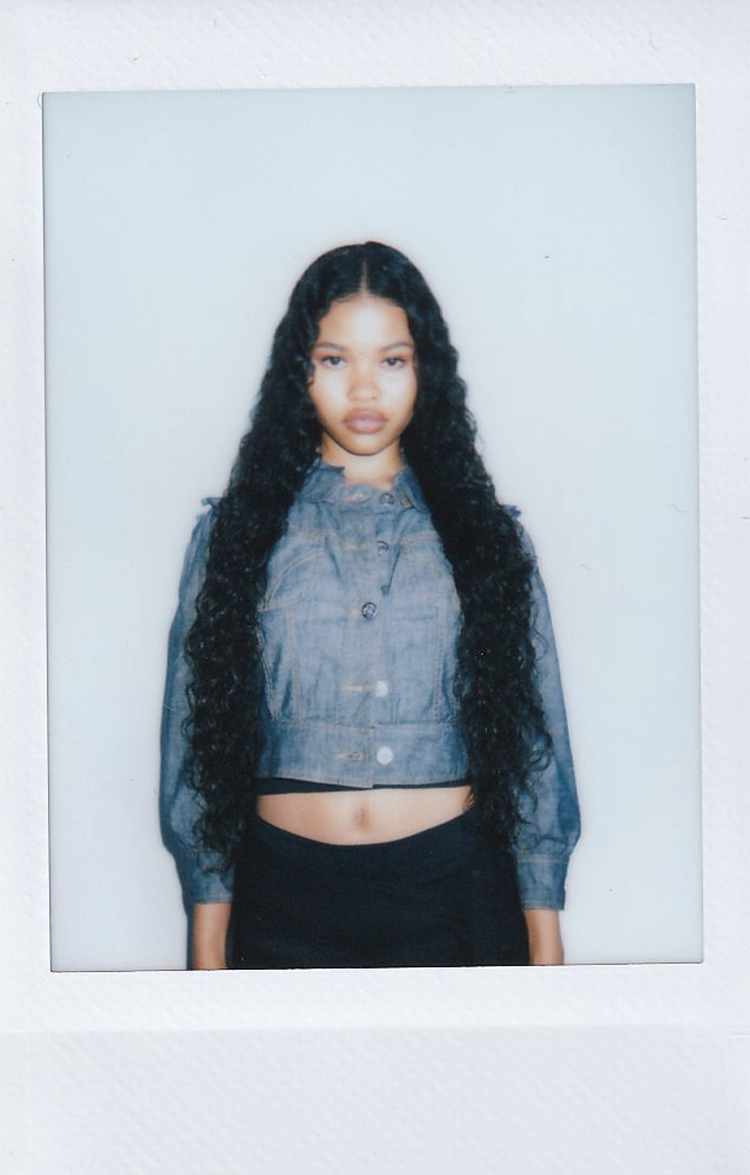 Polaroid of a woman with long dark curly hair in a denim top.