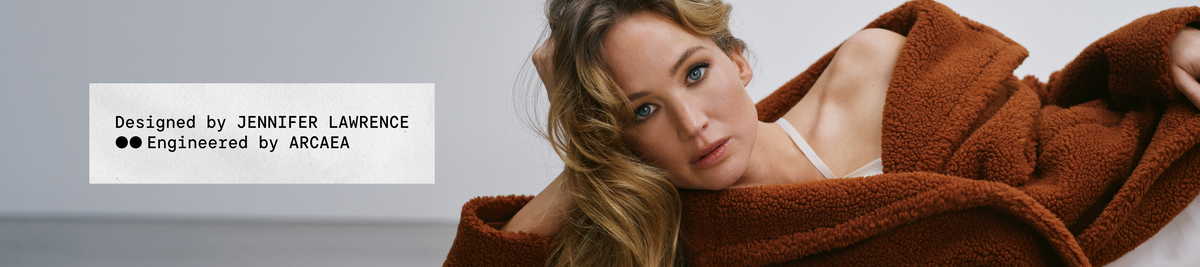 Jennifer Lawrence lying back in a rust teddy coat. Text: Designed by Jennifer Lawrence. Engineered by Arcaea.