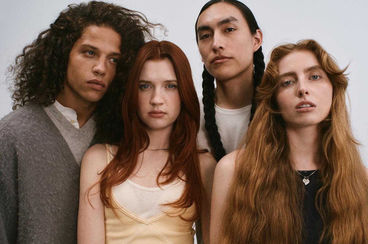 Four members of the cast close together, with curly, red, braided and long auburn hair.