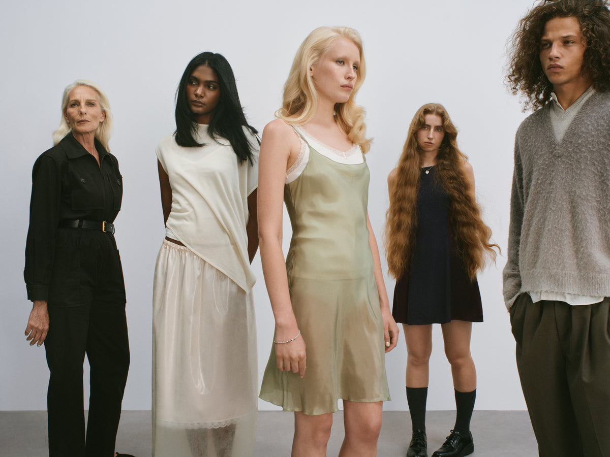 Five members of the mes° cast standing side by side in a studio.