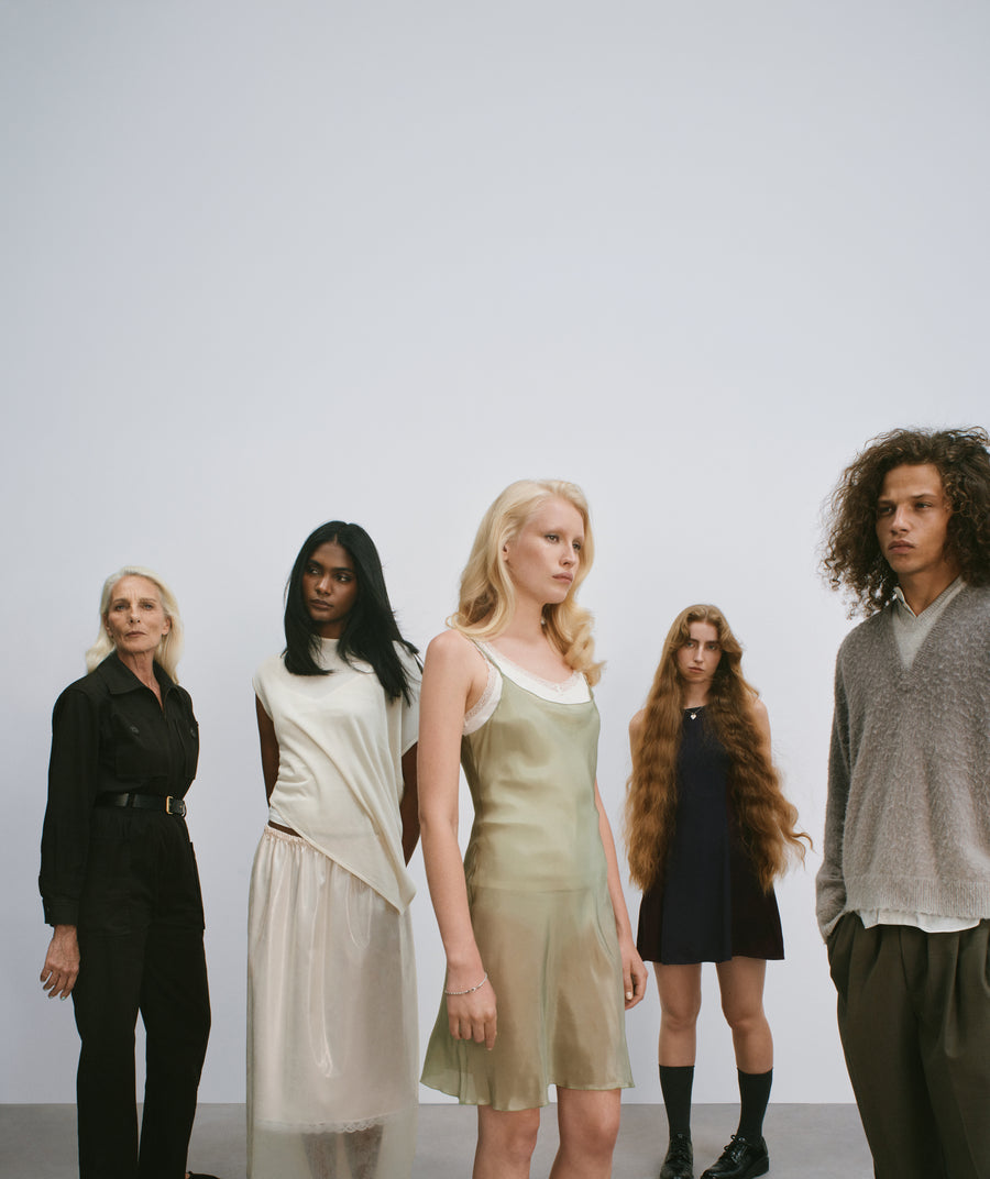 Five members of the mes° cast standing side by side in a studio.